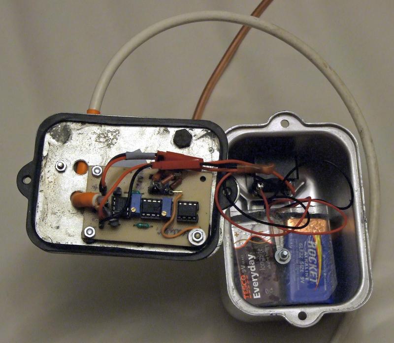 Otwarta komora z elektroniką> Widoczna gumowa uszczelka, płytka, wyłącznik oraz dwie baterie